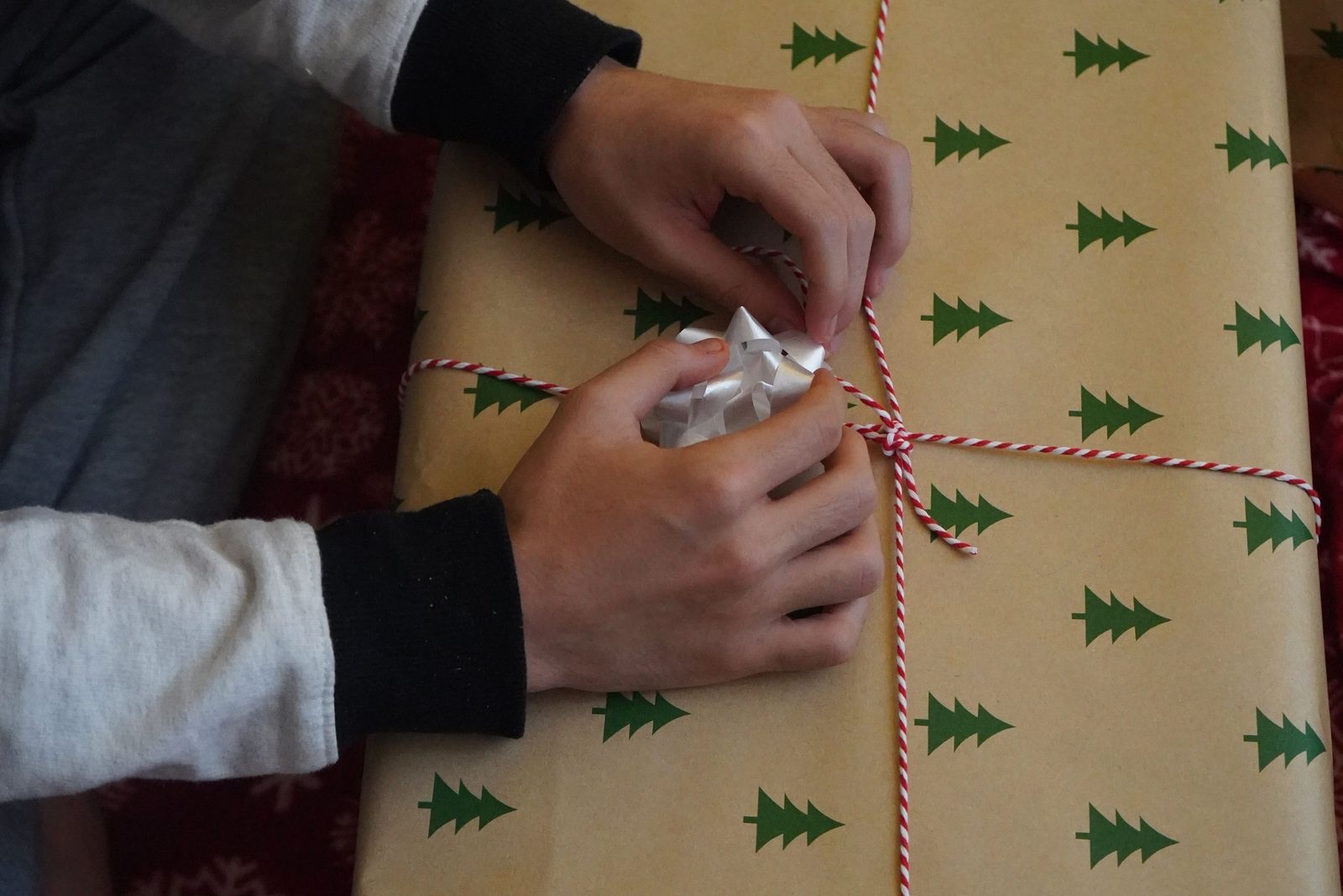 Dłonie pakujące prezent w świąteczny papier ozdobny
